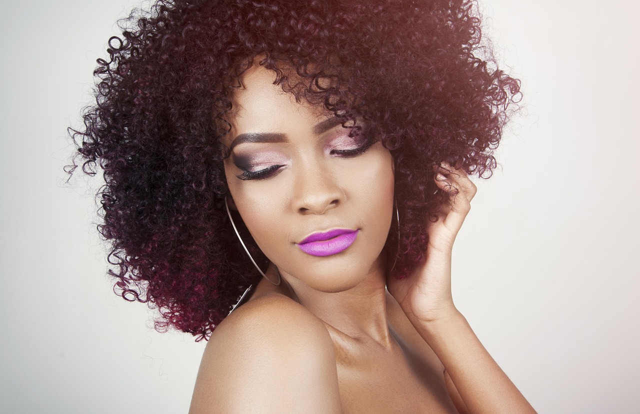 Woman with curly burgundy hair and soft makeup